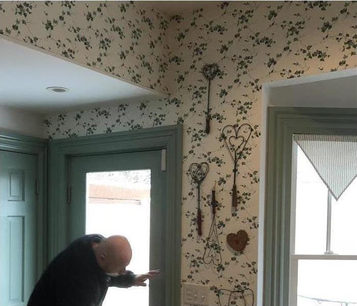 A professional from SERVPRO inspecting the walls of home after storm damage