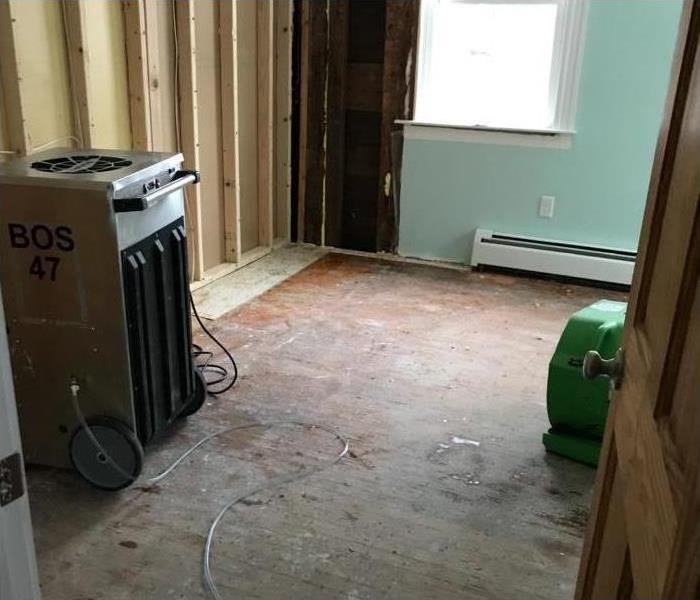 Dehumidifier and air mover placed in an empty room, drywall removed
