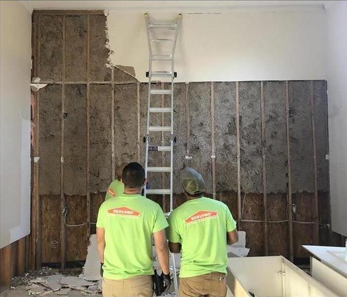 Three workers working in a wall of a home