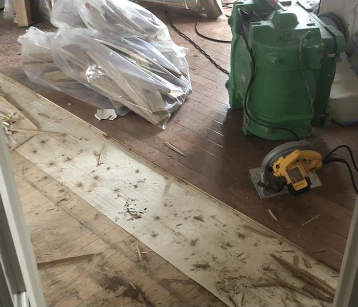 Flooring removal, drying equipment, pieces of floor inside a plastic bag 