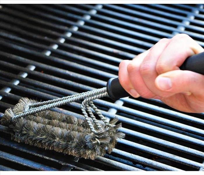 Cleaning a grill at a summer barbecue.