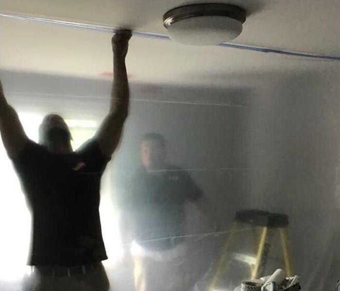 Workers installing plastic covers inside a building. Concept of mold containment
